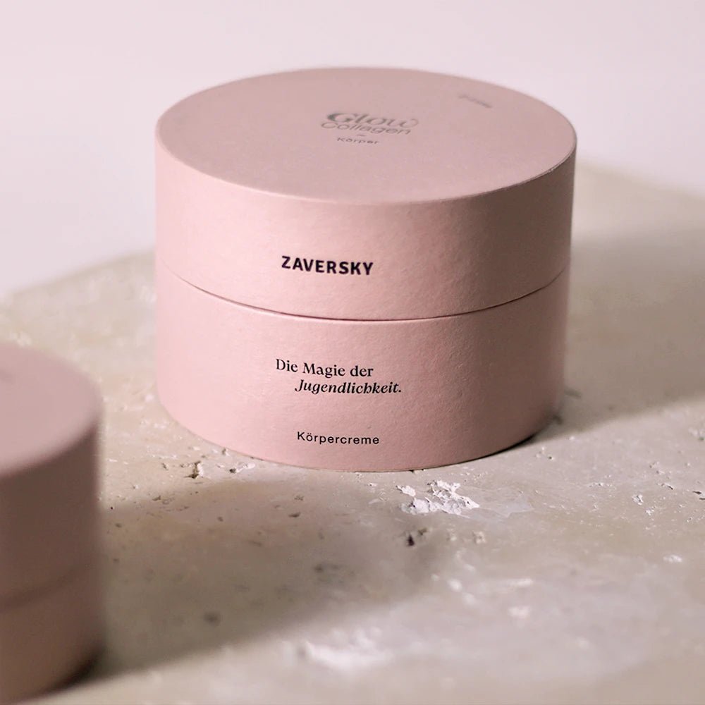 Zaversky Glow Collagen Körpercreme in runder rosa Verpackung mit Aufschrift „Die Magie der Jugendlichkeit“ auf Steinplatte