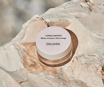 Dolomia Cipria Antietà Puder mit Water Infusion Technology im kleinen Tiegel mit beigem Deckel, präsentiert auf hellem Naturstein.