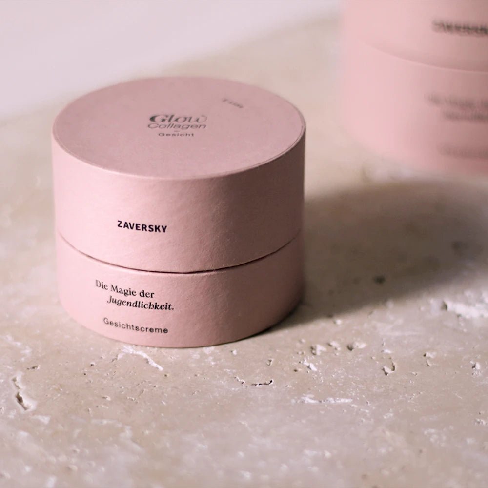 Runde rosa Verpackung der Zaversky Glow Collagen Gesichtscreme mit Aufschrift „Die Magie der Jugendlichkeit“ auf Steinoberfläche