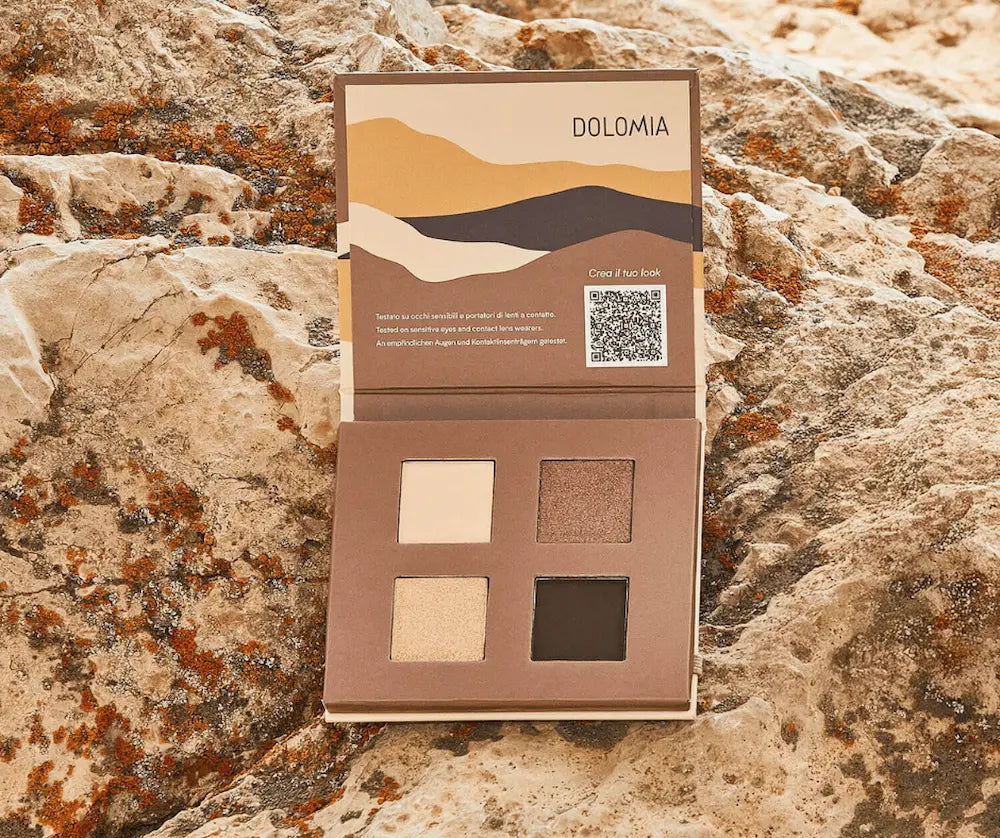 Geöffnete Dolomia Lidschatten-Palette mit vier Farben in Creme, Schimmer-Braun, Hellbeige und Dunkelbraun auf Felsen.