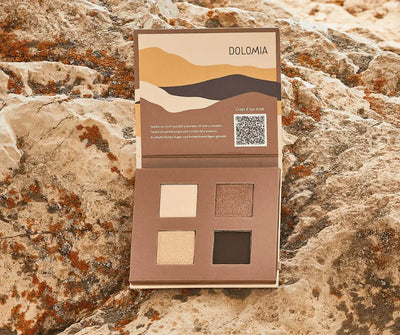 Geöffnete Dolomia Lidschatten-Palette mit vier Farben in Creme, Schimmer-Braun, Hellbeige und Dunkelbraun auf Felsen.
