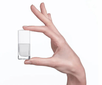 Hand hält ein kleines, eckiges Nagellackfläschchen mit weißem Inhalt und weißem Deckel, Markenschriftzug Dolomia auf der Vorderseite.
