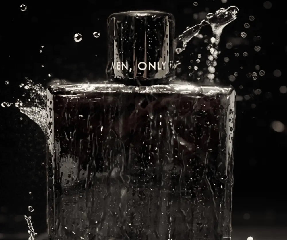 Dunkler Parfumflakon mit Aufschrift „Men, Only For" auf dem Verschluss, umgeben von Wassertropfen vor schwarzem Hintergrund