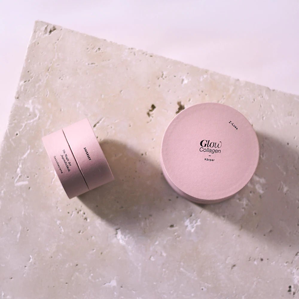 Zaversky Z-Luxe Glow Collagen Körpercreme und Gesichtscreme in rosa Rundverpackungen auf hellem Steinuntergrund